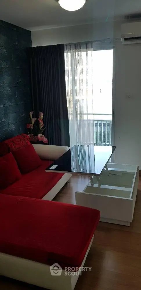 Modern living room with red sofa, glass table, and balcony view in a stylish apartment.