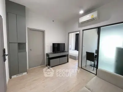 Modern living room with sleek design and air conditioning, featuring a TV and stylish furniture.