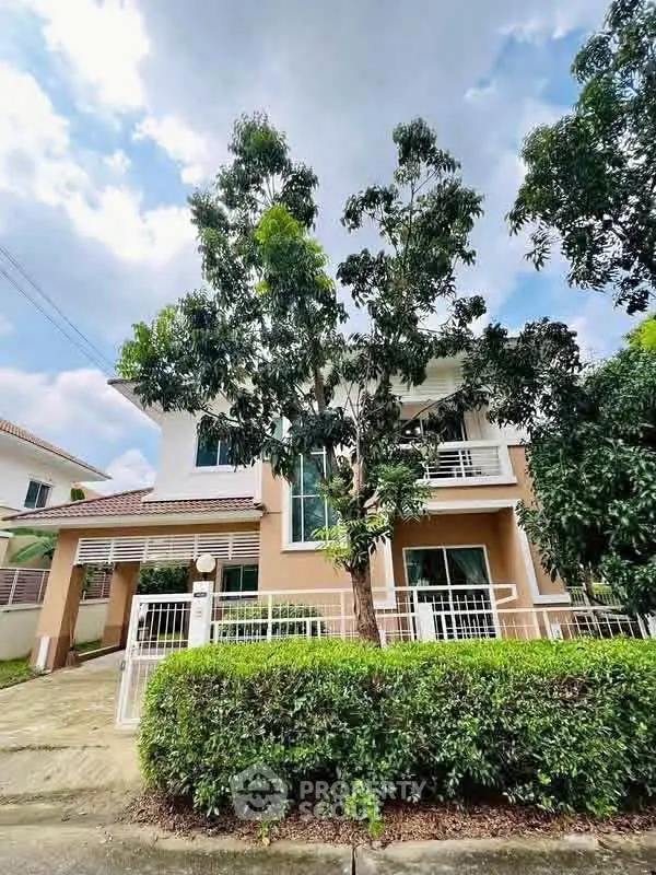 Charming two-story house with lush greenery and modern design in a serene neighborhood.