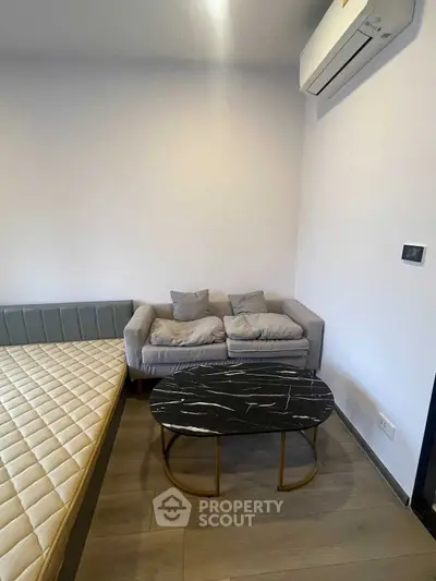 Modern bedroom with stylish sofa and marble coffee table under air conditioning unit.