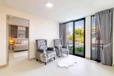 Luxurious living room with elegant armchairs and a view of the garden through large windows.