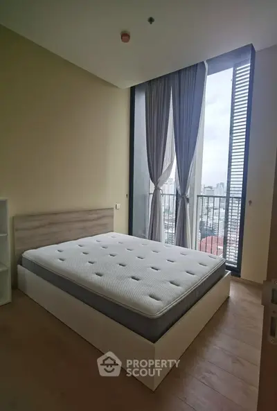 Modern bedroom with large window and city view, featuring a comfortable bed and stylish decor.