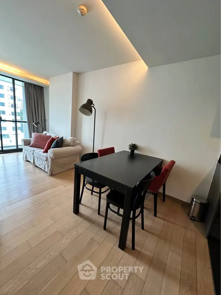 Modern living room with stylish dining area and large windows in a city apartment.