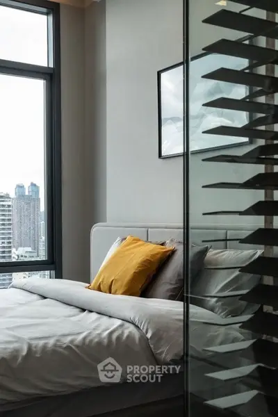 Modern bedroom with city view and stylish decor in high-rise apartment.