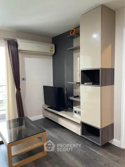 Modern living room with sleek TV unit and air conditioning, featuring stylish decor and natural light.