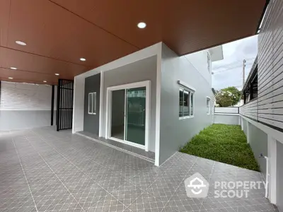 Modern house exterior with spacious tiled patio and green lawn