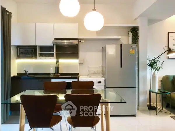 Modern kitchen with sleek design, glass dining table, and stainless steel appliances.