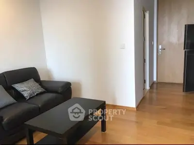 Modern living room with sleek black sofa and wooden flooring, perfect for cozy relaxation.