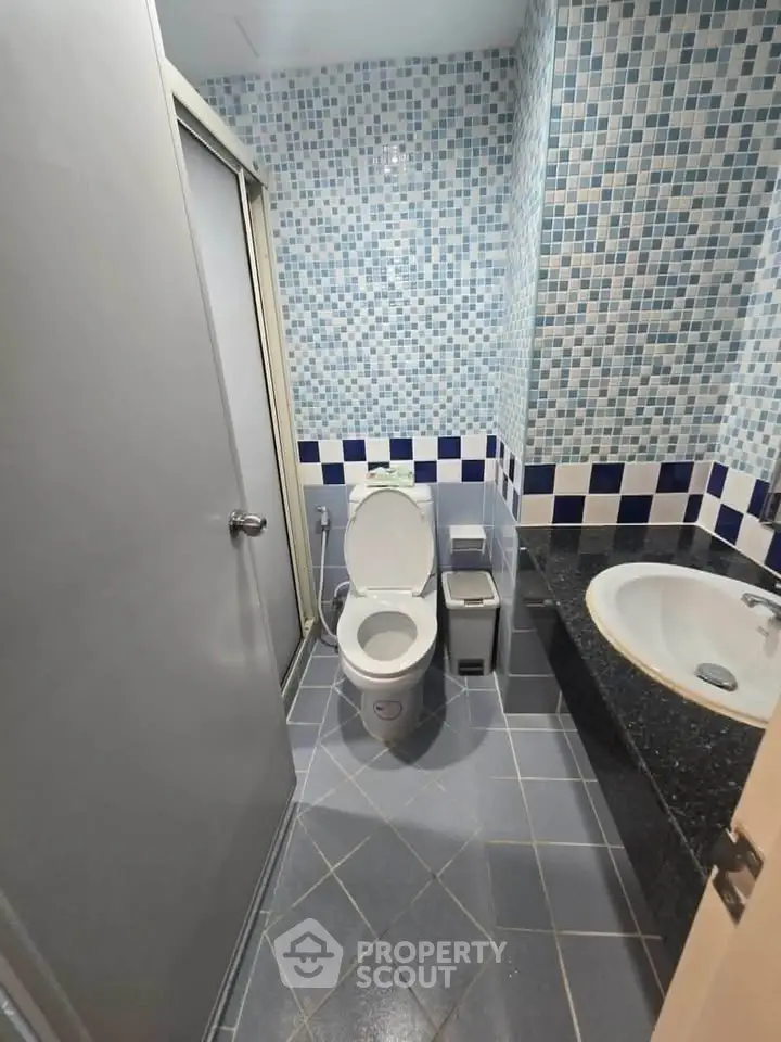 Modern bathroom with mosaic tiles and sleek fixtures in a stylish real estate property.