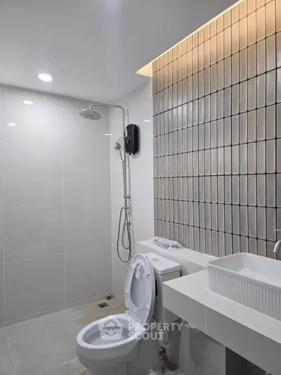 Modern bathroom with sleek design, featuring a rain shower and stylish sink in a contemporary setting.