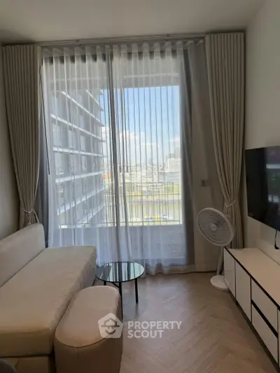 Modern living room with large window and city view, featuring stylish furniture and elegant decor.