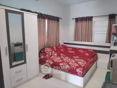 Cozy bedroom with modern furniture and stylish red bedding, perfect for a comfortable living experience.