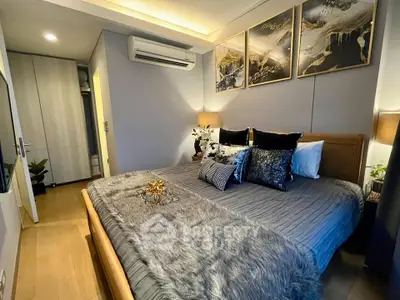 Luxurious bedroom with elegant decor and cozy ambiance, featuring modern art and plush bedding.