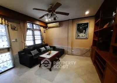 Cozy living room with black leather sofa, wooden coffee table, and ceiling fan.