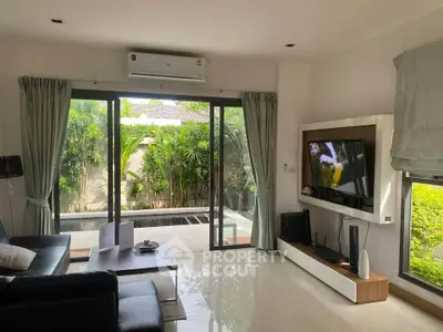 Modern living room with large windows overlooking lush garden, featuring sleek furniture and wall-mounted TV.