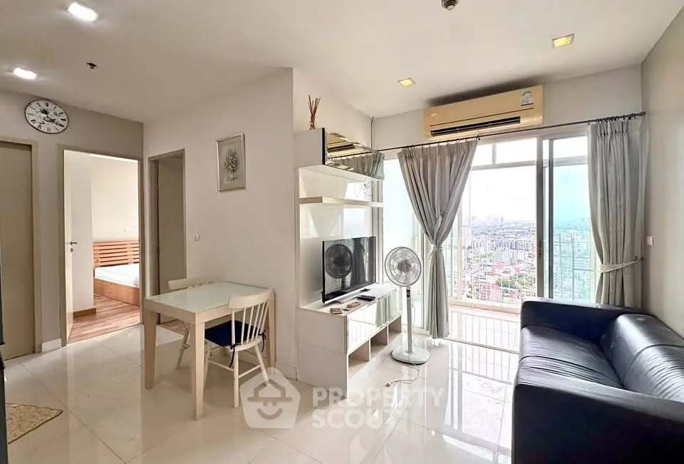 Modern living room with city view, featuring sleek furniture and abundant natural light.