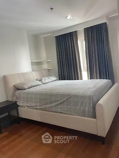 Spacious bedroom with elegant bed and natural light from large window.
