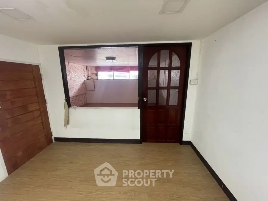 Spacious room with wooden flooring and large window for natural light.