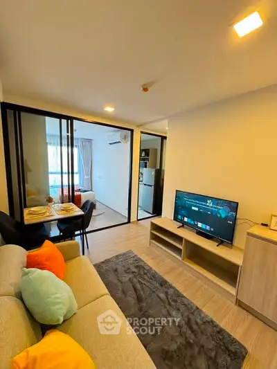 Modern living room with cozy sofa, TV, and dining area in open layout apartment.