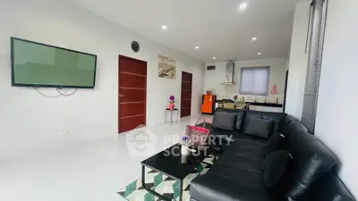 Modern living room with sleek black sofa and wall-mounted TV