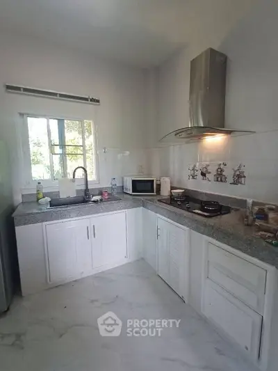 Modern kitchen with sleek countertops and gas stove, featuring ample natural light and contemporary design.