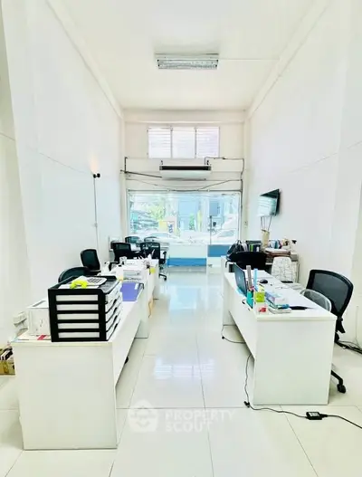 Spacious modern office with sleek white desks and large window for natural light