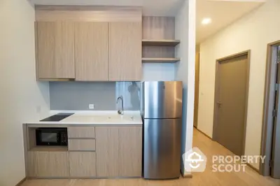 Modern kitchen with sleek cabinetry and stainless steel fridge in minimalist apartment