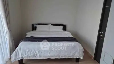 Cozy bedroom with a comfortable bed and natural light from large window.
