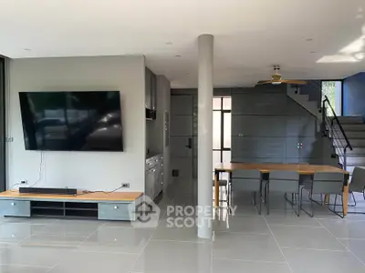 Modern living room with sleek TV setup and stylish dining area, featuring contemporary design and open layout.