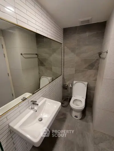 Modern bathroom with sleek design featuring a large mirror and contemporary fixtures.