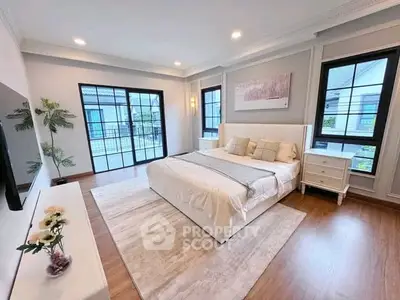 Spacious and elegant bedroom with large windows and modern decor, perfect for relaxation and comfort.