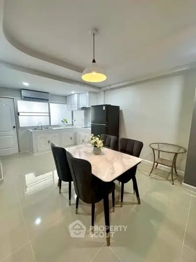 Modern kitchen with dining area featuring sleek black chairs and a marble table, ideal for stylish living.