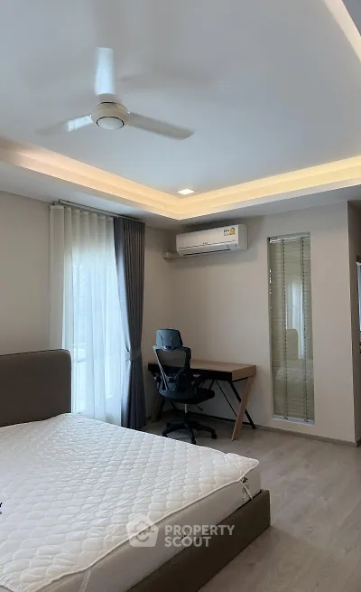 Modern bedroom with study area, featuring a ceiling fan and air conditioning.