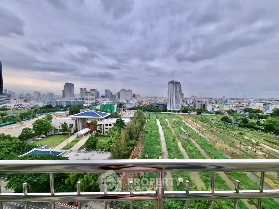 Stunning cityscape view from a high-rise balcony overlooking urban skyline and green fields.