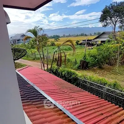 Serene countryside view from a spacious balcony, showcasing lush greenery and distant mountains, ideal for relaxation and nature lovers.