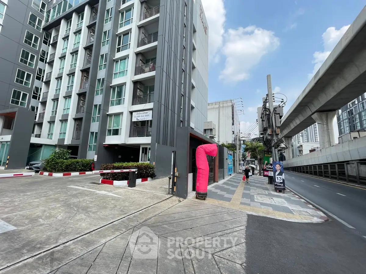 Modern urban apartment building with street view and nearby metro line.