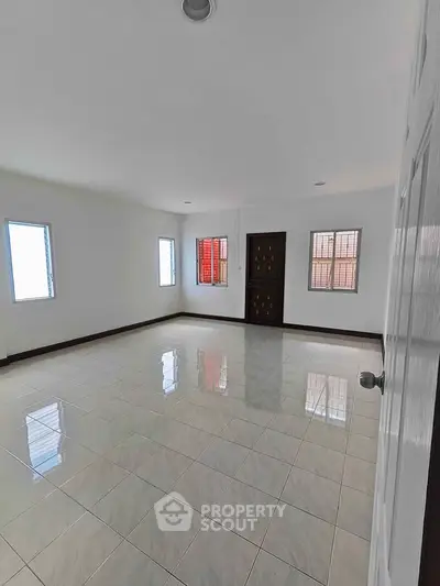 Spacious empty room with tiled floor and three windows for natural light.