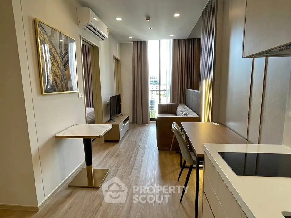 Modern living room with open kitchen, stylish decor, and city view in high-rise apartment.