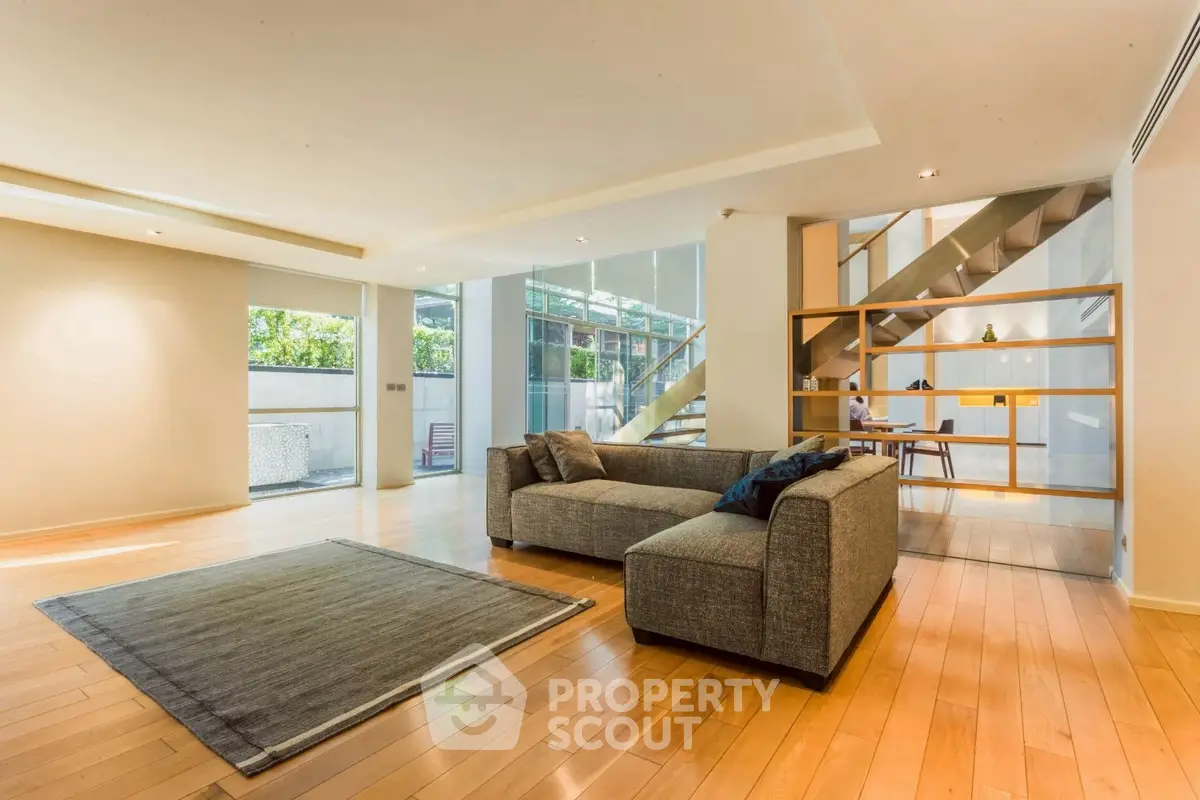 Spacious modern living room with hardwood floors and large windows offering natural light.