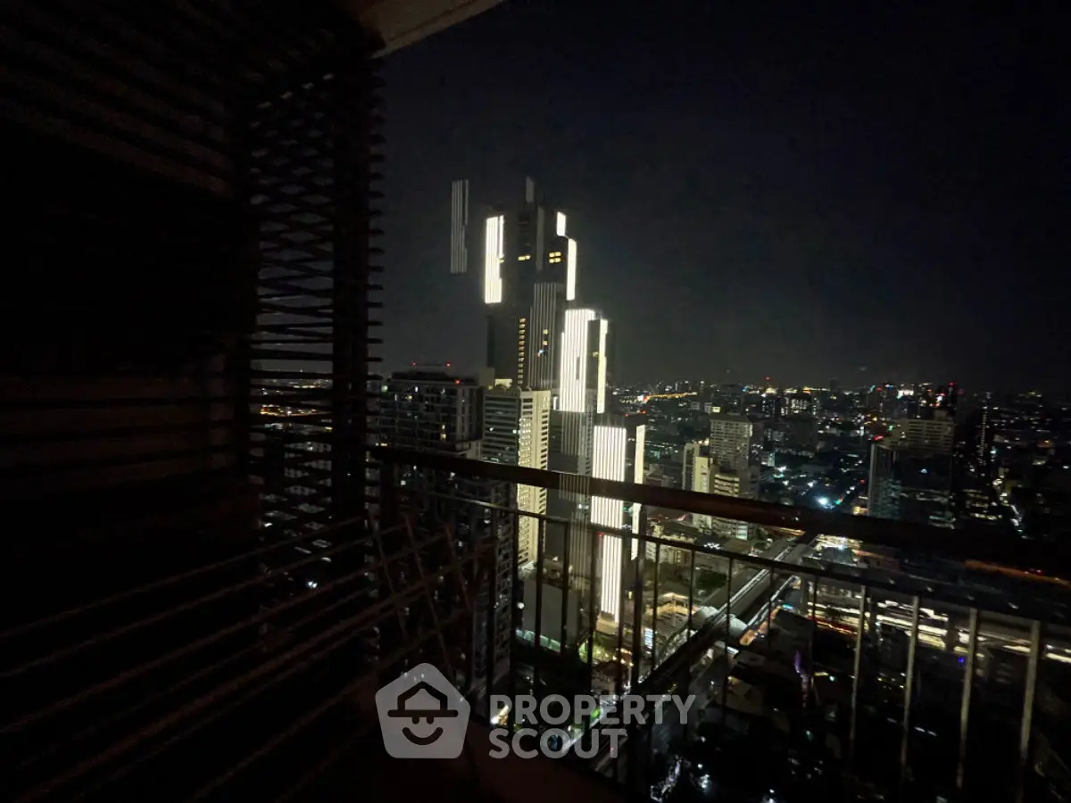Stunning night cityscape view from a high-rise balcony with illuminated skyscrapers.