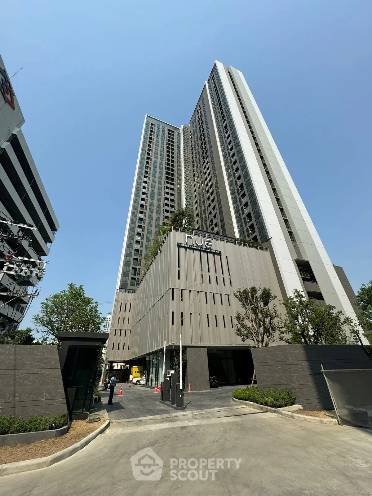 Modern high-rise building with sleek design and lush greenery in urban setting.