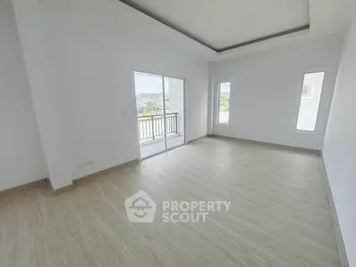 Spacious empty room with large windows and balcony access, perfect for customization.