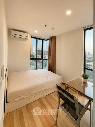 Modern bedroom with city view, featuring large windows and wooden flooring.