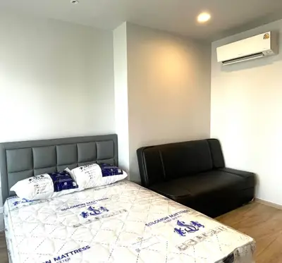 Modern bedroom with stylish bed and sofa, featuring air conditioning and elegant decor.