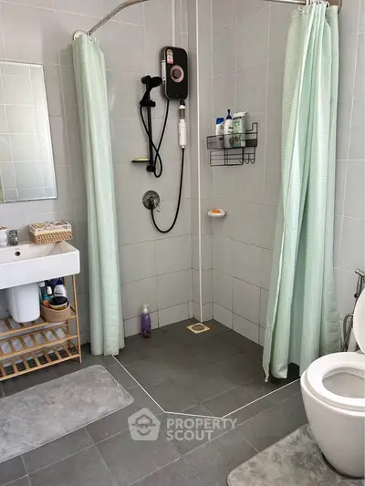 Modern bathroom with shower, sink, and toilet in a sleek tiled design.
