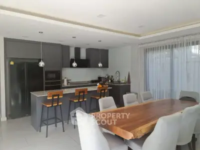 Modern kitchen with sleek design, featuring a large wooden dining table and stylish bar stools.