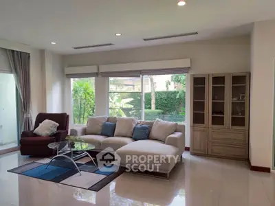 Spacious living room with modern furniture and large windows overlooking a lush garden.
