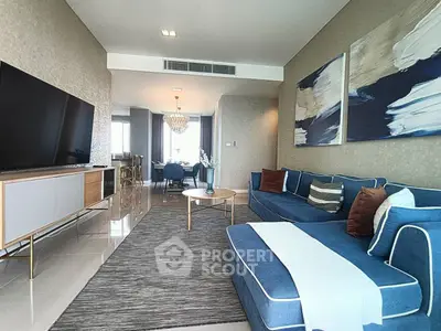 Luxurious modern living room with elegant blue sofas and large TV, perfect for relaxation.