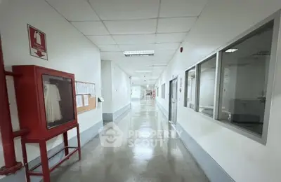 Spacious corridor with fire safety equipment and bulletin board in a modern building.
