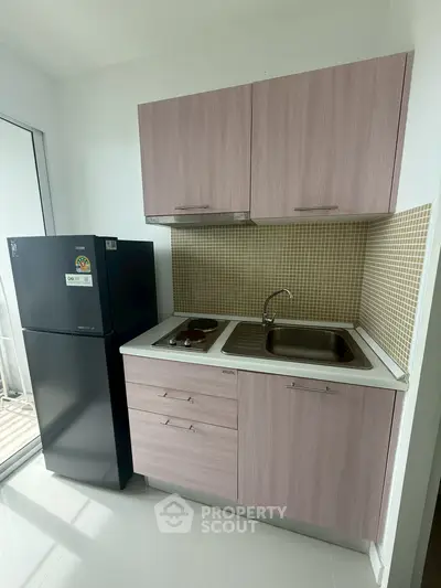 Modern compact kitchen with sleek cabinetry and appliances, perfect for urban living.